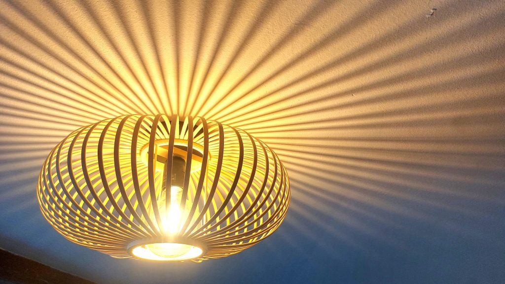 Lampenschirm wirft außergewöhnlichen Schatten an die Decke der Ferienwohnung.