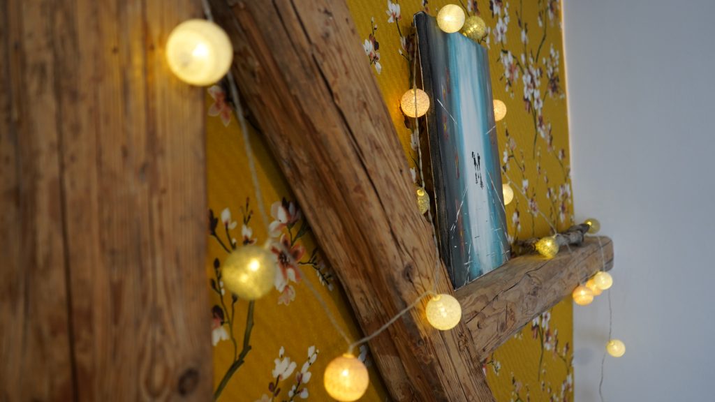 Detailansicht im Schlafzimmer der Unterkunft, mit Gemälde und Lichterkette